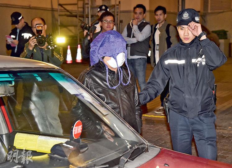 警方昨再在中區放蛇拘捕「黑的」司機。其中一名被捕司機被押走時自行戴上口罩及用紫色環保購物袋作頭套掩面，以避過傳媒鏡頭。（蔡方山攝）