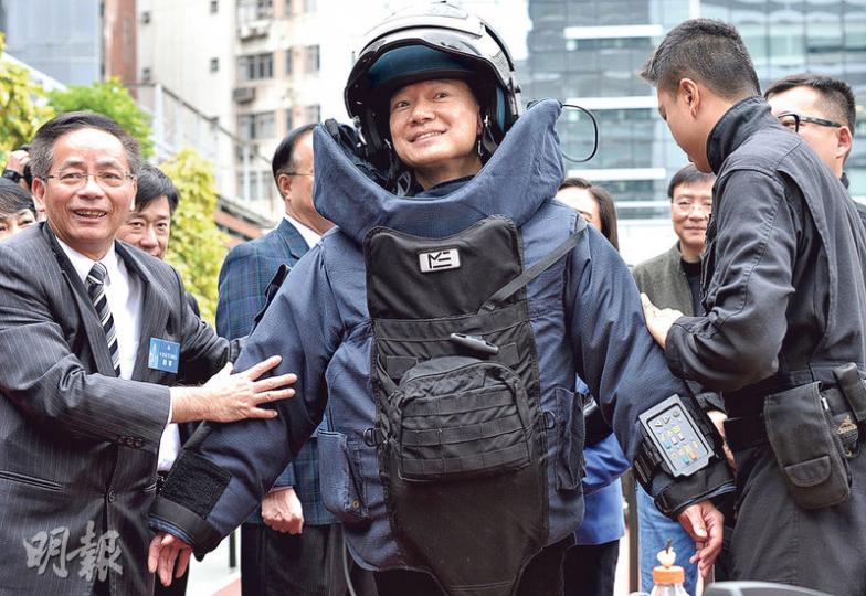 議員謝偉俊（中）試穿總重35公斤嘅拆彈組隊員保護衣，卻舉步維艱，形容好似太空人上月球咁。（蘇智鑫攝）立法會議員參觀警察總部爆炸品處理課，對尋獲嘅戰時炸彈甚感興趣，如李卓人（左）就攞住把玩。（蘇智鑫攝）