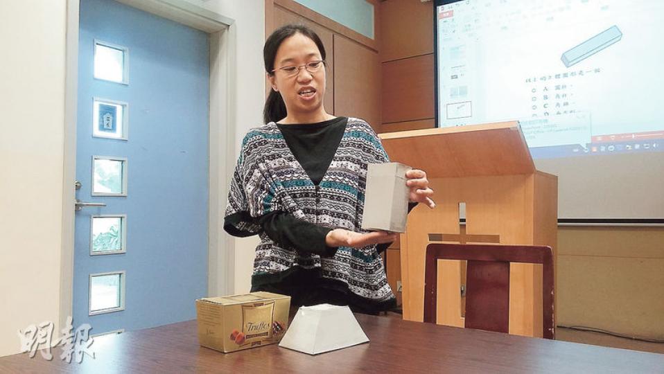 數學科教師陳詩韻舉例，有些朱古力盒（枱上左邊）屬不規則圖形，不在教學範圍，卻屬基本能力，會出現在TSA試題，故她會自製教具解釋角柱體與不規則立體圖形的區別。（田青青攝）