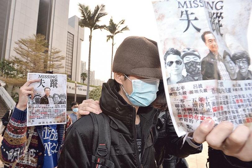 被告林達榮（圖中帶帽者）昨否認一項管有攻擊性武器罪，他離庭時由約10名親友陪同，他們紛紛舉起李波失蹤的宣傳單張，冀喚起市民關注事件。（馮凱鍵攝）