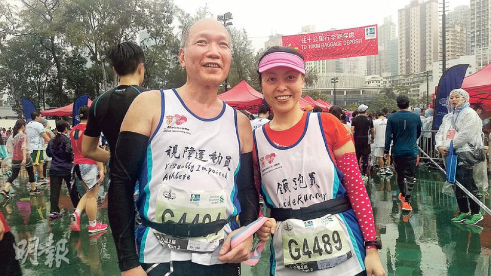 65歲的失明跑手潘先生（左）昨日由領跑員陳小姐（右）陪同參加渣馬10公里賽事，他們表示下雨對表現有影響，但參賽不求勝負及追求成績，希望藉此鼓勵更多視障人士參與馬拉松比賽。（陳柔雅攝）