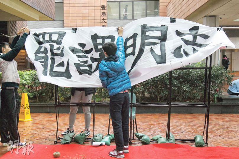 香港大學學生昨起罷課，在國殤之柱旁的黃克競平台舉行罷課集會，罷課委員會成員王俊杰估計約有300名學生參與。（李紹昌攝）昨日天氣陰沉，不時有雨，約300名港大生到國殤之柱旁、有玻璃天幕遮頭的黃克競平台參與集會，「罷課明志」。罷課委員會成員王俊杰承認參與人數未如理想，因宣傳時間較短，該會今日將舉行論壇，希望有更多學生參與罷課。（李紹昌攝）多名學生會後一同製作宣傳橫額，寫下「改革校委驅逐沙皇」及「港大人同命運」字句，呼籲師生參與罷課。（李紹昌攝）