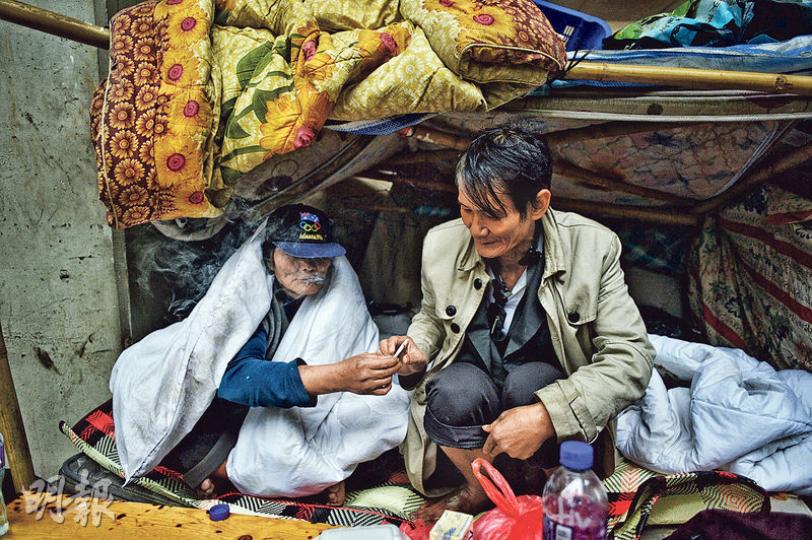 通州街天橋下有一個又一個以木搭成的「小屋」,同住一屋內的郭富(右)和輝哥(左)堅持不入住避寒中心,兩人在寒天下共享一支香煙,郭笑言﹕「(吸了煙)會暖一點。」(蘇智鑫攝) 通州街天橋下有一個又一個以木搭成的「小屋」,同住一屋內的郭富(右)和輝哥(左)堅持不入住避寒中心,兩人在寒天下共享一支香煙,郭笑言﹕「(吸了煙)會暖一點。」(蘇智鑫攝)