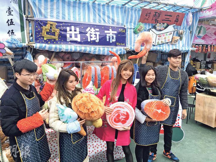 張秀文（中）為賣公仔檔做生招牌。（攝影：楊安莉）何佩瑜（右）及何浩文（左）昨日到維園年宵花市為公司攤位站台。（攝影：楊安莉）