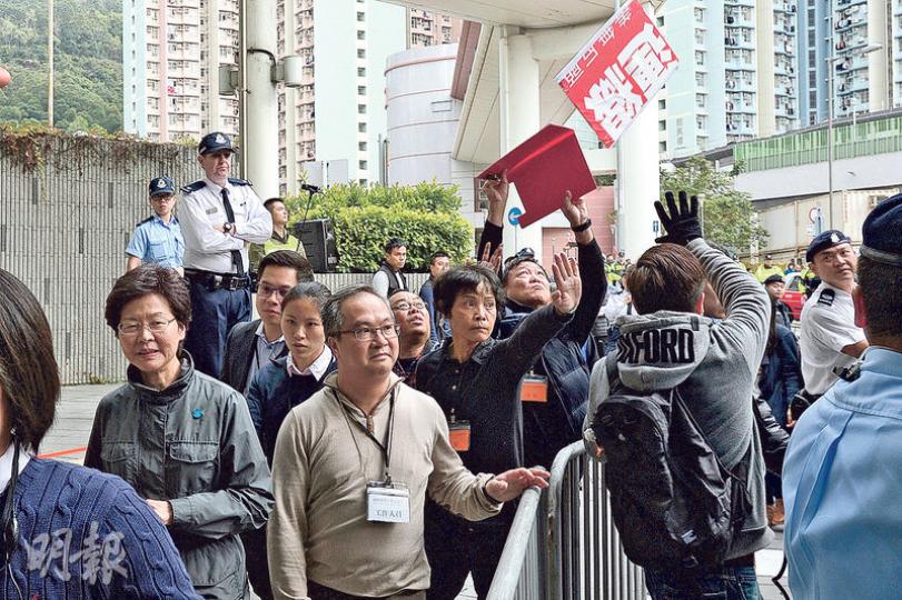 政務司長林鄭月娥在上月出席退保諮議會時,被示威者拋擲的退保文件擲中臉,昨日第二次諮詢會保安明顯加強,以鐵馬把示威區與官員入場通道分隔,中間有警員及保安保護。在林鄭月娥(左)昨日進場時,有示威者向她投擲示威紙牌,保安人員成功攔下。(楊柏賢攝) 政務司長林鄭月娥在上月出席退保諮議會時,被示威者拋擲的退保文件擲中臉,昨日第二次諮詢會保安明顯加強,以鐵馬把示威區與官員入場通道分隔,中間有警員及保安保護。在林鄭月娥(左)昨日進場時,有示威者向她投擲示威紙牌,保安人員成功攔下。(楊柏賢攝)