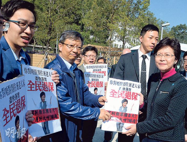 政務司長林鄭月娥（右）昨出席明愛醫院懷明樓開幕禮前，遇民協請願要求全民退保，她接信後離開，在典禮過後亦未有回應傳媒提問。（劉焌陶攝）