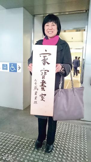 畫家馬家寶於1964年開設的旺角畫室外掛着一個牌匾,寫着「家寶畫室 六歲馬蕭蕭題」。馬蕭蕭(圖)在庭外手持該牌匾的複製品,她表示該牌匾已被「衰人」扔掉,幸好當年曾以同一作品製作書籤,故仍可留念。(張梓鈴攝) 畫家馬家寶於1964年開設的旺角畫室外掛着一個牌匾,寫着「家寶畫室 六歲馬蕭蕭題」。馬蕭蕭(圖)在庭外手持該牌匾的複製品,她表示該牌匾已被「衰人」扔掉,幸好當年曾以同一作品製作書籤,故仍可留念。(張梓鈴攝)