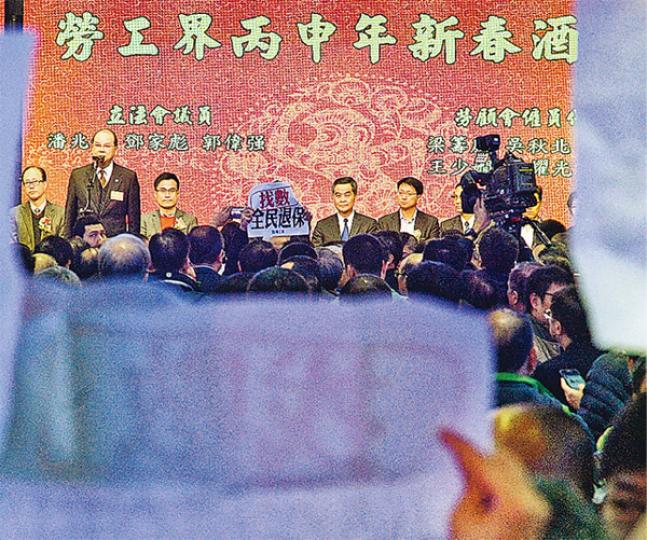 行政長官梁振英(台上左四)昨日出席勞工界新春酒會,在台上與嘉賓祝酒。被保安阻攔的職工盟成員在遠處高呼口號,向梁振英「追數」。(楊柏賢攝)職工盟昨在勞工界酒會狙擊特首梁振英,要求他兌現競選承諾。職工盟副主席郭紹傑(右)說,由於梁不願接請願信,故在場外焚燒信件。(楊柏賢攝) 行政長官梁振英(台上左四)昨日出席勞工界新春酒會,在台上與嘉賓祝酒。被保安阻攔的職工盟成員在遠處高呼口號,向梁振英「追數」。(楊柏賢攝)職工盟昨在勞工界酒會狙擊特首梁振英,要求他兌現競選承諾。職工盟副主席郭紹傑(右)說,由於梁不願接請願信,故在場外焚燒信件。(楊柏賢攝)
