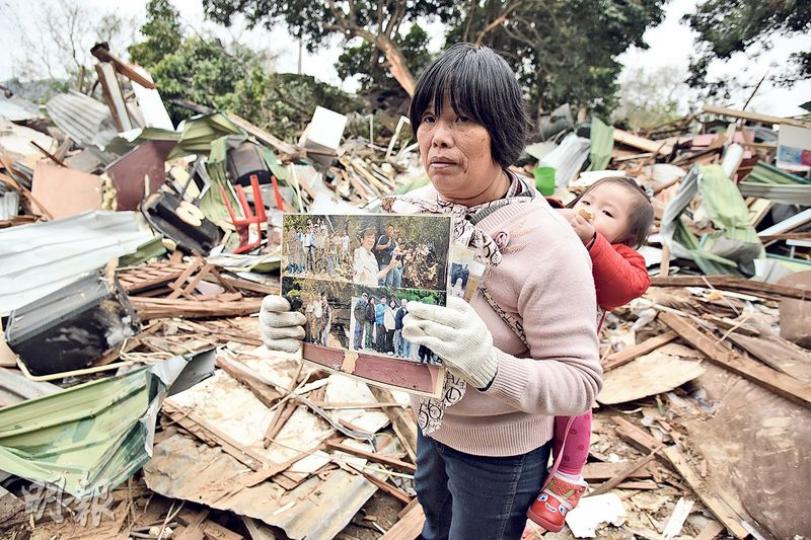 黃先生昨帶同兒孫親友回村內執拾物品,黃氏一家居於上址逾50年,家園突然被毁,祖先的神主牌、家庭照,及與亡妻的遺照亦碎散廢墟中。圖為親友揹着黃的孫女回村內尋回舊照。(鍾炳然攝) 黃先生昨帶同兒孫親友回村內執拾物品,黃氏一家居於上址逾50年,家園突然被毁,祖先的神主牌、家庭照,及與亡妻的遺照亦碎散廢墟中。圖為親友揹着黃的孫女回村內尋回舊照。(鍾炳然攝)