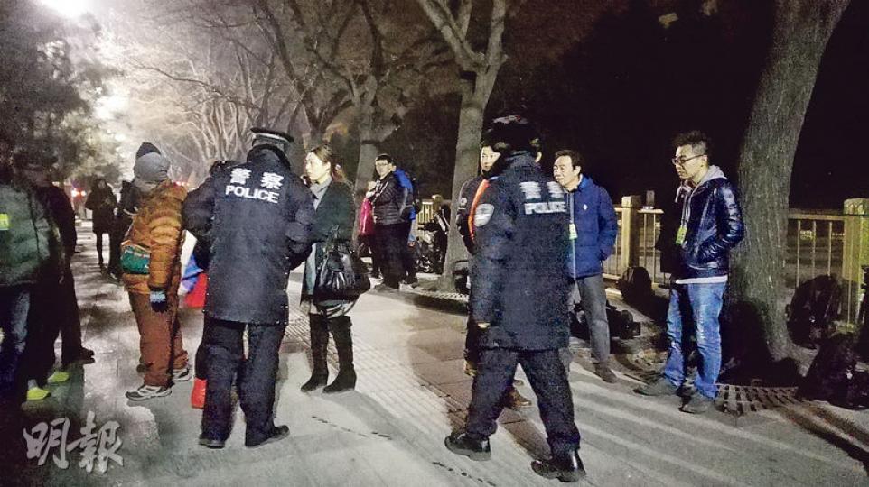 兩名警察在檢查排隊記者的證件,並帶走兩名不是記者的人。(明報記者攝) 兩名警察在檢查排隊記者的證件,並帶走兩名不是記者的人。(明報記者攝)
