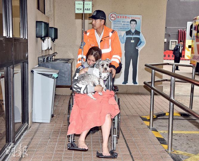 起火單位女住客送院時緊抱愛犬,她因5隻愛貓葬身火海,顯得非常傷心。(蔡方山攝) 起火單位女住客送院時緊抱愛犬,她因5隻愛貓葬身火海,顯得非常傷心。(蔡方山攝)