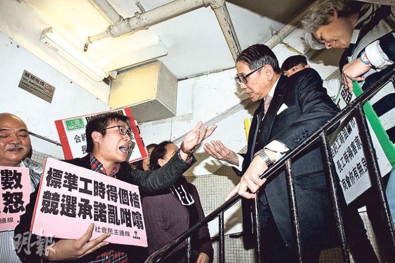 職工盟、社民連及街工等30多人昨早在標準工時委員會開會前到場抗議,社民連副主席黃浩銘(左一)要求梁智鴻(右二)准許示威者代表列席,梁智鴻不同意,黃浩銘與一眾示威者最後稱要「護送」梁上樓,在門外張貼標語。(李紹昌攝) 職工盟、社民連及街工等30多人昨早在標準工時委員會開會前到場抗議,社民連副主席黃浩銘(左一)要求梁智鴻(右二)准許示威者代表列席,梁智鴻不同意,黃浩銘與一眾示威者最後稱要「護送」梁上樓,在門外張貼標語。(李紹昌攝)
