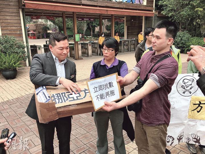 二級廚師林先生（遞信者）指挪亞方舟度假酒店拖欠個人工資等共4.5萬元，昨與香港廚師聯盟及街坊工友服務處到挪亞方舟要求回應，並製造一艘紙製「挪亞方舟」，要求對方接收。酒店人事部經理李國雄（左）出來接信及紙船，並指已交到勞工處跟進事件。（王慧瓊攝）
