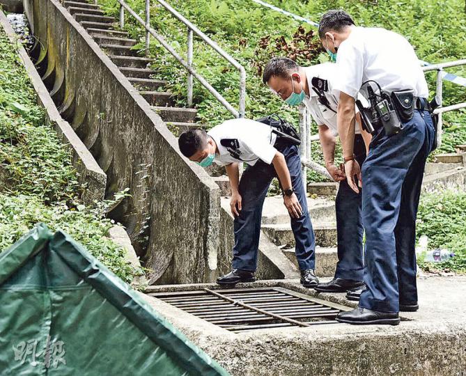 屯門良景邨對開一個沙井昨發現失蹤老翁屍體後，警方趕至將死者屍體由沙井內搬出，用帳篷掩蓋（左下方）並調查；其間警員低頭察看沙井內情况，以了解死者伏屍沙井原因。（張嘉雯攝）
