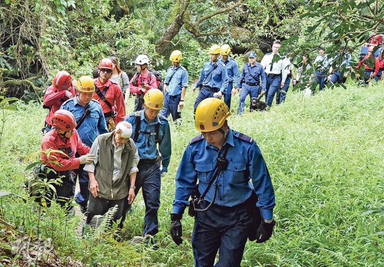 粉嶺老翁掃墓迷路，警方、消防、民安隊聯同飛行服務隊展開大規模陸空搜救，至昨午終尋回失蹤逾1日老翁，合力扶他落山送院治理，大團圓結局。（林智傑攝）當傳出父親平安被尋回後，兒子（左）隨即趕上山與父親（右）會合，之後一直蹲在父親身旁遞上餅乾及清水，並關心慰問：「夠唔夠水飲呀？」（林智傑攝）