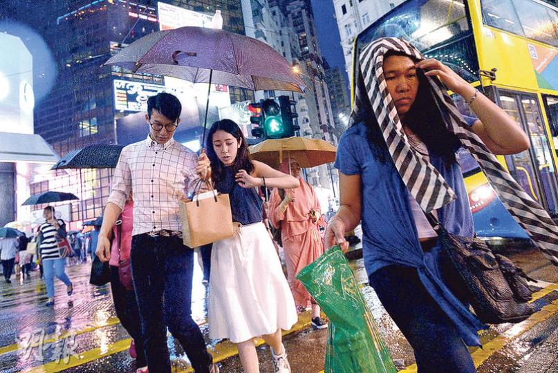 受一道低壓槽相關雷雨區影響，本港天氣昨午忽然轉壞，天文台於下午4時35分發出黃色暴雨警告信號，為時接近3小時。大嶼山、大埔及屯門錄得逾10毫米雨量，北區更錄得逾30毫米，市區雨勢相對較小，但傍晚一度錄得每小時逾20公里的陣風，夾雜雨水打在途人身上，顯得相當狼狽。（楊柏賢攝）