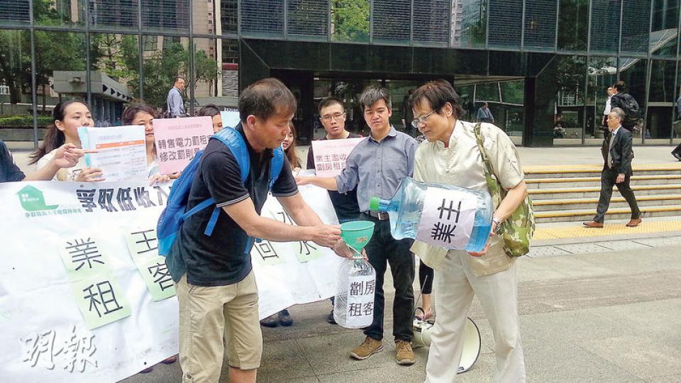 示威者把水由貼上「業主」字樣的水樽，倒入貼上「劏房租客」字樣的水樽內，象徵業主要向租客「回水」。（羅霜寧攝）