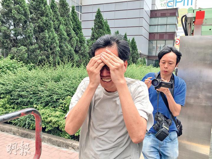 於球場更衣室偷拍男休班警的男倉務員陸泳明(左),昨獲釋後掩面離開觀塘裁判法院,並一直面露笑容。(黃建邦攝) 於球場更衣室偷拍男休班警的男倉務員陸泳明(左),昨獲釋後掩面離開觀塘裁判法院,並一直面露笑容。(黃建邦攝)