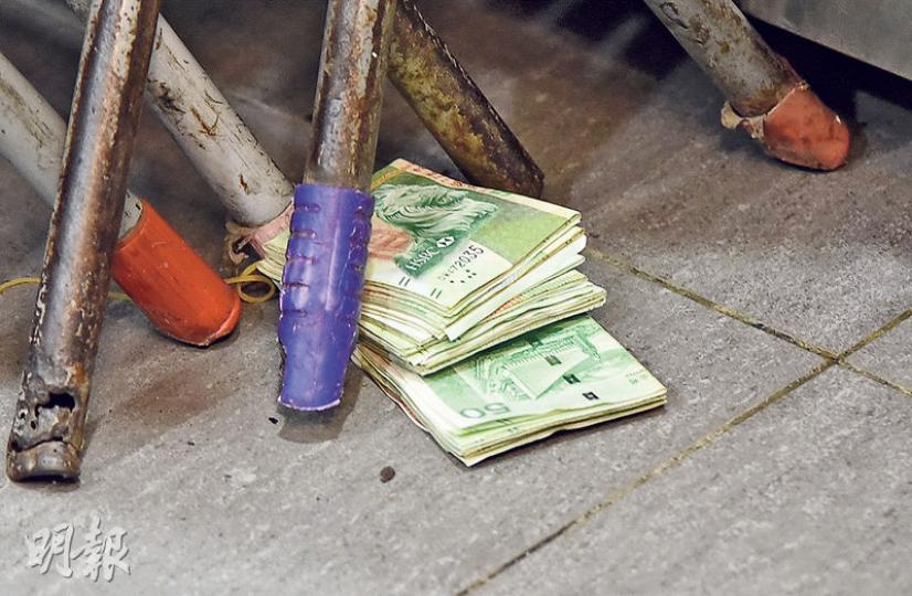 警員在小食店水吧枱下檢獲一疊約值5000元的50元鈔票,不排除竊賊因「騰雞」及摸黑逃走,遺下部分贓款。(蔡方山攝) 警員在小食店水吧枱下檢獲一疊約值5000元的50元鈔票,不排除竊賊因「騰雞」及摸黑逃走,遺下部分贓款。(蔡方山攝)