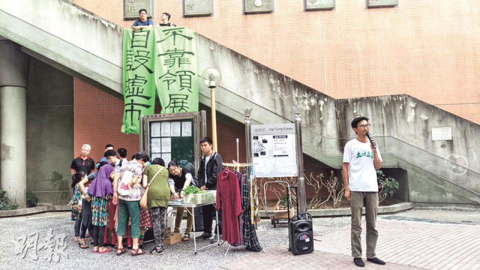 土地正義聯盟繼早前到逸東邨舉辦市集後，昨日約10名成員到該邨的圓形廣場外，掛起「自設墟市 不靠領展」直幡，收集居民對自設墟市意見，居民最關心墟市管理權、價錢及衛生問題等。在旁則設有以物易物攤檔，吸引多名居民換物。（陳柔雅攝）土盟擺檔期間，自稱為該區房屋署人員的黎先生（前排右一）指攤檔阻街，要求停止活動，令在場者不滿。土盟執委朱凱迪（前排右二白衣者）要求黎與居民對話，拉鋸近半小時後，最終黎稱願意對話。有5名居民就街市及屋邨管理相關議題發問，朱凱迪則在一旁計時。（陳柔雅攝）