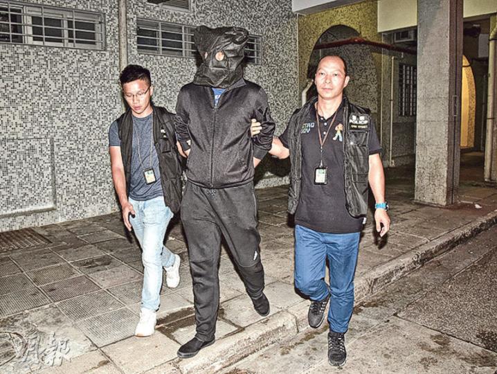 涉嫌勒索陀地費不遂傷人被捕的黑漢,昨凌晨黑布蒙頭押返其上水天平邨平怡樓寓所搜查。(蔡方山攝) 涉嫌勒索陀地費不遂傷人被捕的黑漢,昨凌晨黑布蒙頭押返其上水天平邨平怡樓寓所搜查。(蔡方山攝)
