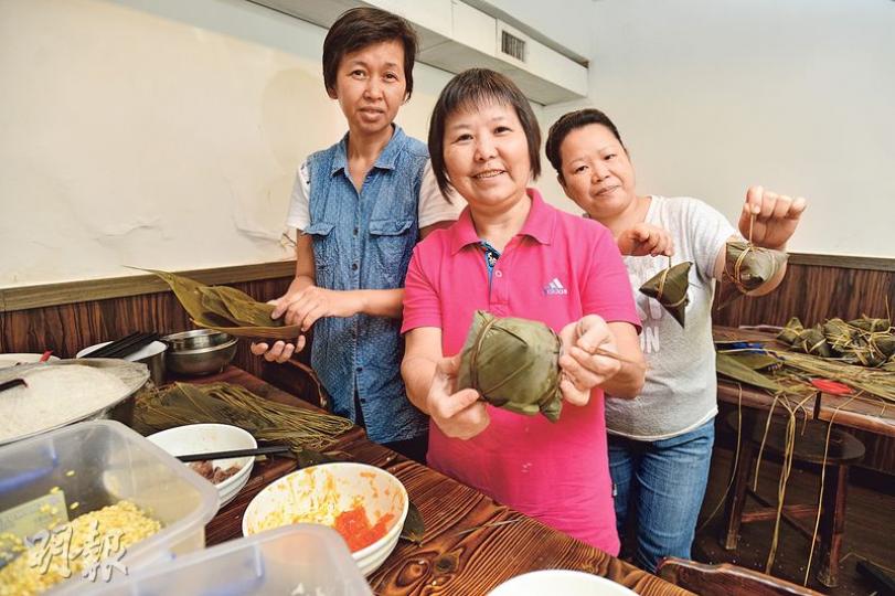 數片竹葉在家庭主婦手上,可輕易變成不同形狀的糉。訪問當日所見,Merry(中)主力包較高難度的五角糉,新加入的阿霞(右)負責三角糉。Eva(左)看似手藝純熟,但原來她近日才重新向Merry學習包四角糉的技巧。(黃志東攝)一班參與社企項目「共廚家作」的基層婦女,早前每個清晨都爭取烤魚店開店前的閒置時間,運用食肆廚房及地方,為顧客包逾千隻糉。其中一名家庭主婦阿霞(圖)說從未試過為如此多人煮食,盼今個端午節為他人帶來自家味道。(黃志東攝) 數片竹葉在家庭主婦手上,可輕易變成不同形狀的糉。訪問當日所見,Merry(中)主力包較高難度的五角糉,新加入的阿霞(右)負責三角糉。Eva(左)看似手藝純熟,但原來她近日才重新向Merry學習包四角糉的技巧。(黃志東攝)一班參與社企項目「共廚家作」的基層婦女,早前每個清晨都爭取烤魚店開店前的閒置時間,運用食肆廚房及地方,為顧客包逾千隻糉。其中一名家庭主婦阿霞(圖)說從未試過為如此多人煮食,盼今個端午節為他人帶來自家味道。(黃志東攝)
