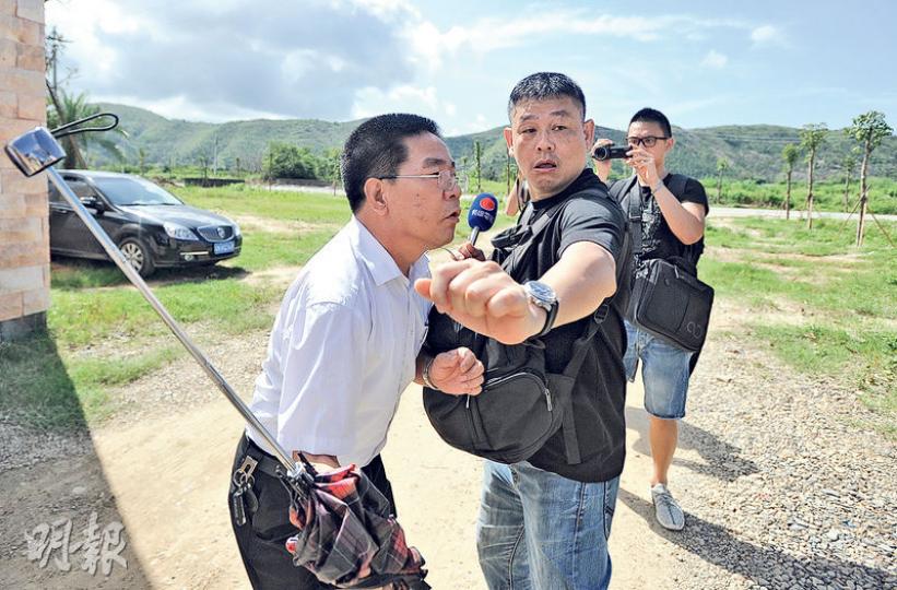 管轄烏坎村的東海鎮副鎮長錢漢沛(左)呵斥記者「像狗一樣」,不僅推搡記者,還作勢要打人。圖為錢漢沛揮遮打人時被在場記者阻攔。(明報記者攝) 管轄烏坎村的東海鎮副鎮長錢漢沛(左)呵斥記者「像狗一樣」,不僅推搡記者,還作勢要打人。圖為錢漢沛揮遮打人時被在場記者阻攔。(明報記者攝)