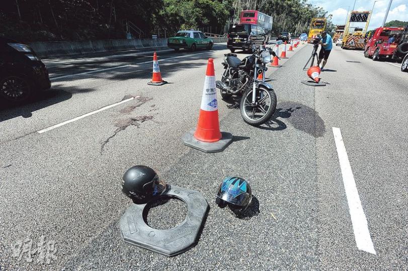 電單車切線時疑撞上「雪糕筒」失控，人仰車翻，被撞雪糕筒頂部亦甩脫，事後現場留下兩名傷者的頭盔。（衛永康攝）