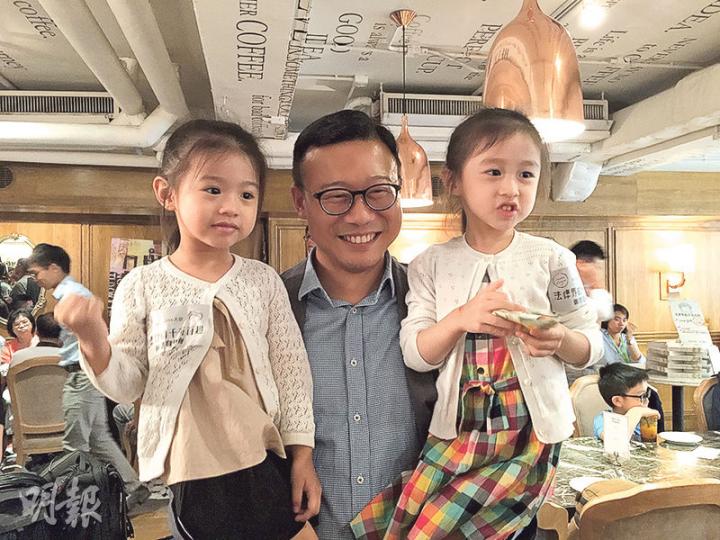 民建聯副主席張國鈞（中）出新書講法律界趣聞，成家人到場支持，包括4歲大女芷喬（右）同3歲細女苡喬（左），近日積極健身操fit自己嘅佢一個月已減咗20磅，一次過抱起兩個女都無難度。（何曉勤攝）