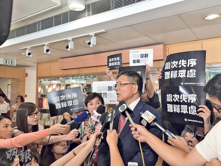 廣播處長梁家榮與員工會晤後見記者，交代會面情况，其間多名工會員工手舉「歲次失序     難釋眾慮」的標語以示不滿。（張嘉雯攝）