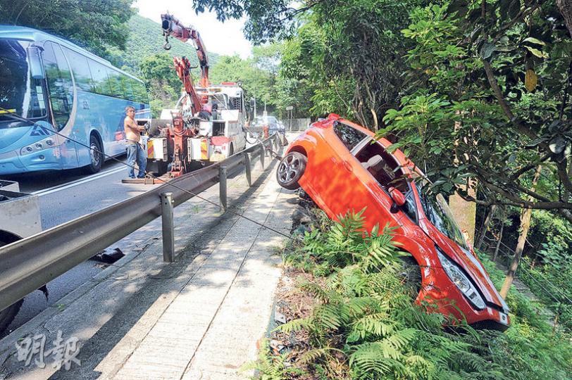 紅色跑車失控剷上斜壆,飛墜山坡,車輛事後由拖車拉回路邊。(衛永康攝) 紅色跑車失控剷上斜壆,飛墜山坡,車輛事後由拖車拉回路邊。(衛永康攝)