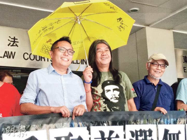被告梁國雄(中)及譚得志(左)昨在庭外與約10名支持者高叫「爭取普選無罪,政治打壓可恥」的口號,又指是因林鄭月娥「小氣」,當局才檢控他們。(植敏欣攝) 被告梁國雄(中)及譚得志(左)昨在庭外與約10名支持者高叫「爭取普選無罪,政治打壓可恥」的口號,又指是因林鄭月娥「小氣」,當局才檢控他們。(植敏欣攝)
