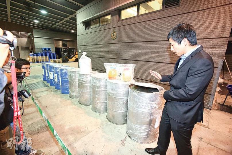 海關毒品調查科指揮官葉國樑講述偵破「蠱惑油桶」藏毒案詳情。油桶上右邊的淺黃色液體為檢獲的液態可卡因,左邊深黃色為作掩飾的食用棕櫚油,並可見約1厘米高的暗格。(伍浦鋒攝) 海關毒品調查科指揮官葉國樑講述偵破「蠱惑油桶」藏毒案詳情。油桶上右邊的淺黃色液體為檢獲的液態可卡因,左邊深黃色為作掩飾的食用棕櫚油,並可見約1厘米高的暗格。(伍浦鋒攝)