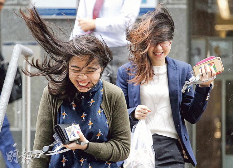 颱風「莎莉嘉」吹襲下，本港各區天氣一度非常惡劣，市民冒着狂風驟雨上班上學，狼狽不堪。圖為中環昨日午膳時間，上班族沿交易廣場天橋步往IFC時遇上大風。（郭慶輝攝）
