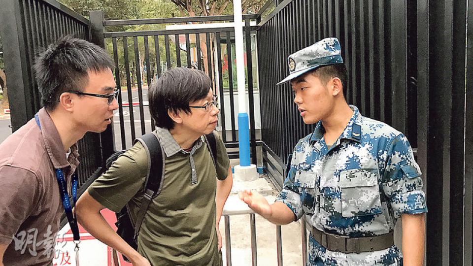 意外後，兩名民航處職員到石崗軍營跟進事故原因，其間向駐守的解放軍查詢。（林智傑攝）
