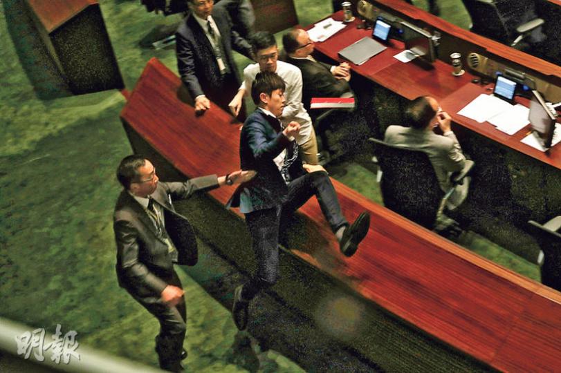 鄭松泰在會議廳議員桌椅之間「跨欄」,擺脫保安阻截。(李紹昌攝) 鄭松泰在會議廳議員桌椅之間「跨欄」,擺脫保安阻截。(李紹昌攝)