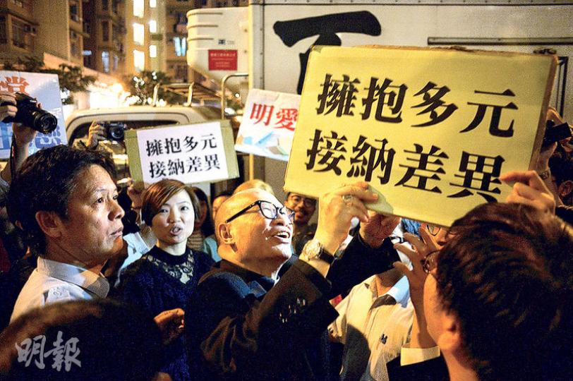 剛獲任命助理主教的楊鳴章(黑框眼鏡者)在記者會後被明愛專上學院的學生包圍,要求他解釋早前將同性戀比喻吸毒的說法。楊鳴章澄清該說法屬傳媒錯誤引述,強調自己尊重不同性傾向者。(鍾林枝攝) 剛獲任命助理主教的楊鳴章(黑框眼鏡者)在記者會後被明愛專上學院的學生包圍,要求他解釋早前將同性戀比喻吸毒的說法。楊鳴章澄清該說法屬傳媒錯誤引述,強調自己尊重不同性傾向者。(鍾林枝攝)