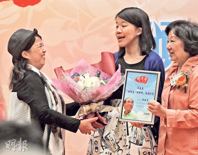 基督教聖約教會堅樂中學中文科教師陳穎雯(中)患先天顎骨張合困難,手術後曾遭學生嘲笑,但以寬容感化學生。她今年獲得「好老師獎」,其母親(左)於頒獎時上台送花祝賀。(李紹昌攝) 基督教聖約教會堅樂中學中文科教師陳穎雯(中)患先天顎骨張合困難,手術後曾遭學生嘲笑,但以寬容感化學生。她今年獲得「好老師獎」,其母親(左)於頒獎時上台送花祝賀。(李紹昌攝)