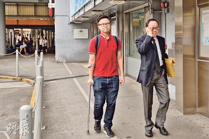 城大專業進修學院學生莫嘉傑（左）昨在律師莊永燦（右）的陪同下，到旺角法律援助處申請法援。莫早前參與「反辱華反港獨」集會後遇上車禍，右腳韌帶斷裂，需撐拐杖出行。（楊柏賢攝）