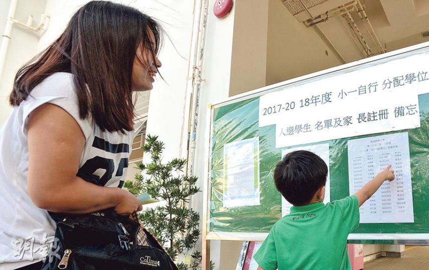 雙非家長張太（左）昨帶同準備升小一的兒子到報讀的鳳溪創新小學看自行收生結果。張太說原已「打定輸數」，沒想過兒子獲取錄，母子均感萬分高興，兒子更歡喜地指着自己的名字。 （楊柏賢攝）
