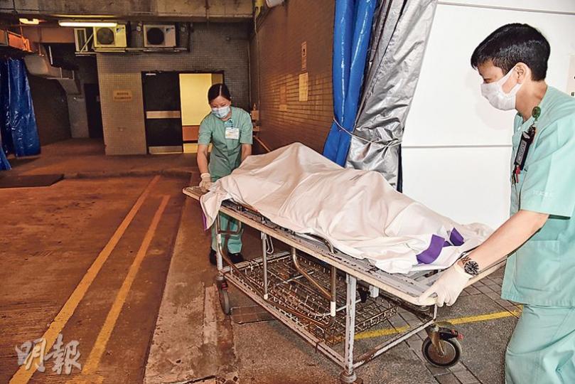 死者遺體由飛行服務隊直升機吊起運往醫院，待親友趕抵醫院見其最後一面，才舁送殮房。（林智傑攝） 死者兒子（中間戴眼鏡者）昨早接獲尋回父親的消息後，趕到現場山腳等候，其後從救援人員得悉父親已死，接回其父行山時攜帶的紅色背囊。（鍾炳然攝）