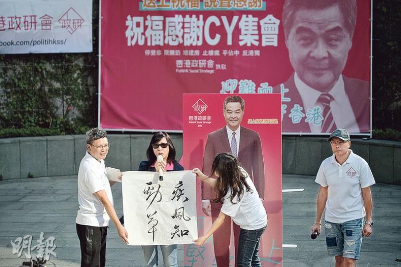 香港政研會噚日喺政總外舉行「祝福感謝CY集會」，準備咗唔少打氣道具，包括有兩米高紙板CY，同「疾風知勁草」墨寶。左一為政研會主席鄧德成。（蘇智鑫攝）噚日撐CY集會出席者以中老年人為主，包括前港區全國人大代表曹宏威（左三），同上屆特首選舉提名CY嘅體育小組選委貝鈞奇（左五）。（蘇智鑫攝）