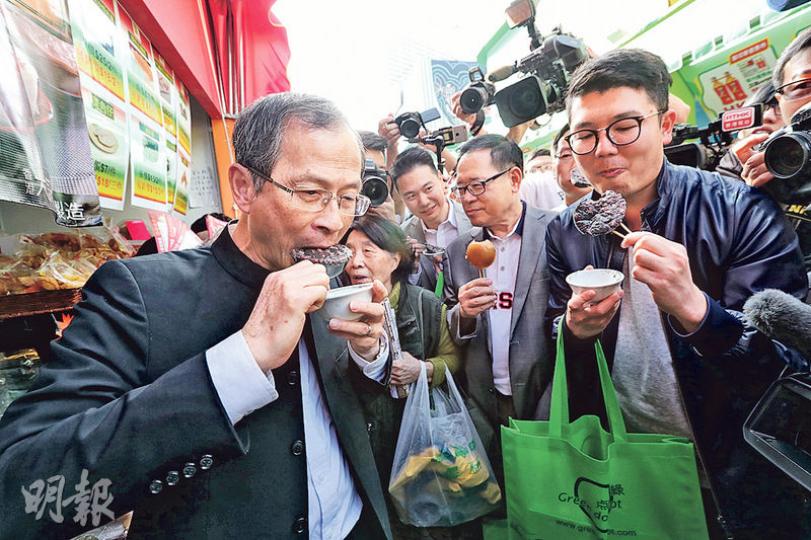 立法會前主席曾鈺成(左一)「拉隊」逛工展會,幫襯缽仔糕攤檔時,有人起哄話寓意官運「步步高陞」,佢聽完即刻大口咬啖。(李紹昌攝) 立法會前主席曾鈺成(左一)「拉隊」逛工展會,幫襯缽仔糕攤檔時,有人起哄話寓意官運「步步高陞」,佢聽完即刻大口咬啖。(李紹昌攝)