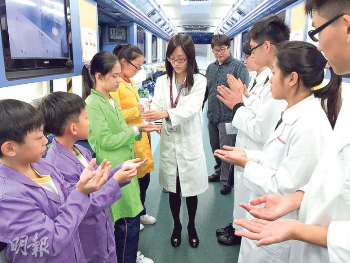 可譽的流動實驗室可供學生做不同科研實驗,例如圖中講師在學生手上噴上發光顯影劑後,學生可在紫外光燈下檢視手上有多少細菌。流動實驗室每次出勤時都有講師、實驗室技術員及所需實驗儀器,租金每天一般為8000元。(黃津琪攝)可譽流動實驗室講師楊德慧正把大腸桿菌的DNA放在凝膠電泳系統作分析,後方是顯示屏,即場顯示講師的實驗動作,讓車上同學都可清晰看見。(黃津琪攝) 可譽的流動實驗室可供學生做不同科研實驗,例如圖中講師在學生手上噴上發光顯影劑後,學生可在紫外光燈下檢視手上有多少細菌。流動實驗室每次出勤時都有講師、實驗室技術員及所需實驗儀器,租金每天一般為8000元。(黃津琪攝)可譽流動實驗室講師楊德慧正把大腸桿菌的DNA放在凝膠電泳系統作分析,後方是顯示屏,即場顯示講師的實驗動作,讓車上同學都可清晰看見。(黃津琪攝)