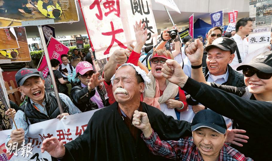 一名潘姓老翁(前中)頭戴假髮、身穿黑袍遊行,旁邊人士則作狀出拳打他,大喊「打倒狗官」。潘受訪時否認扮法官,稱自己似「黑色的鬆毛狗」,被問行為會否涉及藐視法庭時,他回應指「梁振英都被人叫狼,為何不可以話法官呢?」(李紹昌攝)包括香港政研會、保衛香港運動等多個組織昨午遊行,聲稱支持七警和警隊執法,抗議司法不公。遊行隊伍由中環遮打花園出發,前往金鐘警察總部送上心意卡後,再到政府總部露天廣場集會。大會指有3500人參與,警方則指最高峰有1800人。(李紹昌攝) 一名潘姓老翁(前中)頭戴假髮、身穿黑袍遊行,旁邊人士則作狀出拳打他,大喊「打倒狗官」。潘受訪時否認扮法官,稱自己似「黑色的鬆毛狗」,被問行為會否涉及藐視法庭時,他回應指「梁振英都被人叫狼,為何不可以話法官呢?」(李紹昌攝)包括香港政研會、保衛香港運動等多個組織昨午遊行,聲稱支持七警和警隊執法,抗議司法不公。遊行隊伍由中環遮打花園出發,前往金鐘警察總部送上心意卡後,再到政府總部露天廣場集會。大會指有3500人參與,警方則指最高峰有1800人。(李紹昌攝)