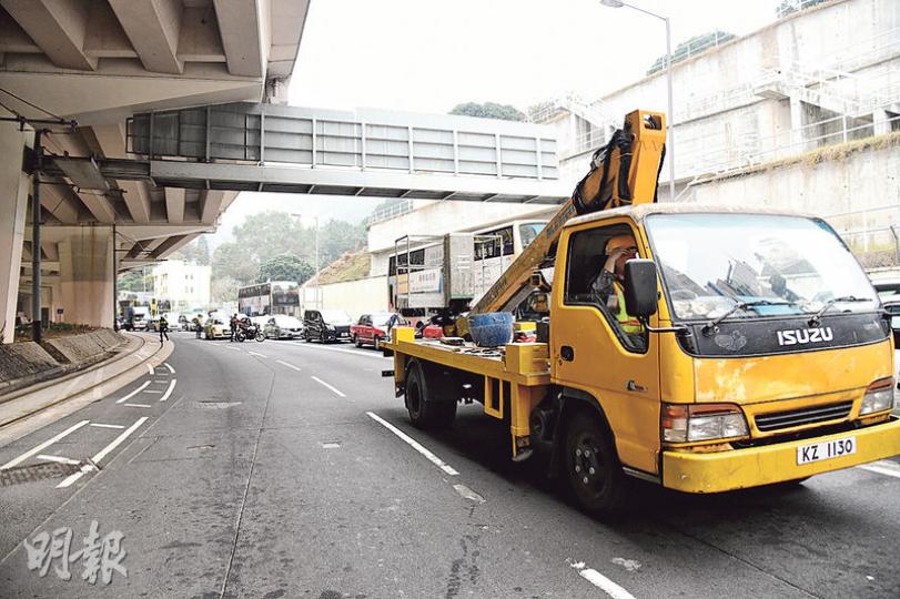 跑馬地黃泥涌道近厚德里行車天橋底昨晨發生石屎剝落（近指示牌位置），幸未造成傷亡；警員封鎖現場，由人員架起升降台車（右）檢查，並把不穩石屎部分拆卸，約個多小時後解封。（蔡方山攝）現場所見，橋墩排水管位置明顯有石屎崩裂情况，並露出疑似鏽蝕的鋼筋。（蔡方山攝）