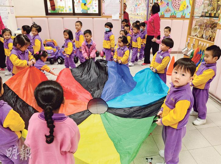 荃灣商會朱昌幼稚園其中一項遊戲學習活動，是由學生合作拿起一塊以不同顏色的布合併而成的大布，再把一個球放在布上，合力阻止球體跌進布中央的洞。校長林翠玲說，學生可從中學習合作精神、顏色、數目、形狀等。（劉焌陶攝）