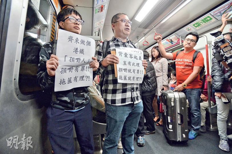 本土派梁金成(左二)不滿港鐵最近嘅廣告針對孭背囊嘅乘客,但又無同時提醒拖篋等乘客,噚日拎住「港鐵玩批鬥 背囊客起義」標語搭港鐵抗議,但加埋佢只有兩個人參加。(楊柏賢攝) 本土派梁金成(左二)不滿港鐵最近嘅廣告針對孭背囊嘅乘客,但又無同時提醒拖篋等乘客,噚日拎住「港鐵玩批鬥 背囊客起義」標語搭港鐵抗議,但加埋佢只有兩個人參加。(楊柏賢攝)