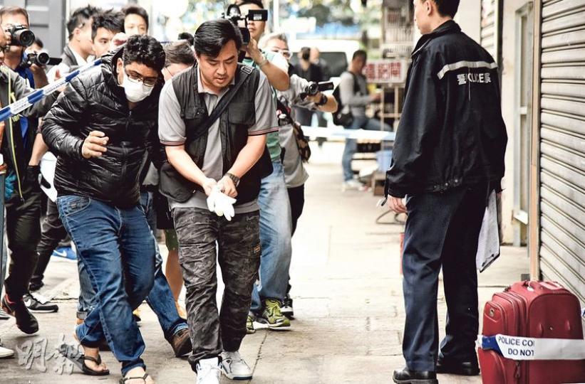 昨午重案組探員帶同遇劫印度商人（戴口罩者）到尋回兩個行李篋的唐樓協助調查，初步點算證實未有損失。圖右下為案中其中一個行李篋。（陳柔雅攝）警方根據具GPS功能手機資料，迅即在大角嘴洋松街16號一幢唐樓地下及梯間，尋回兩個被搶行李篋，帶署進一步檢驗。（陳柔雅攝）
