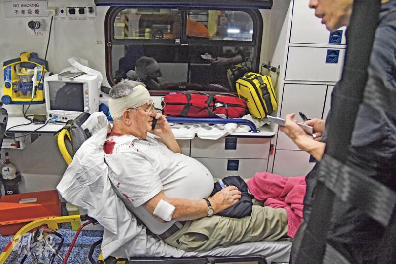 灣仔街頭傷人案中,77歲外籍男事主遭人用硬物擊至頭破血流,幸傷勢不嚴重,在救護車上仍可使用手提電話。(蔡方山攝) 灣仔街頭傷人案中,77歲外籍男事主遭人用硬物擊至頭破血流,幸傷勢不嚴重,在救護車上仍可使用手提電話。(蔡方山攝)